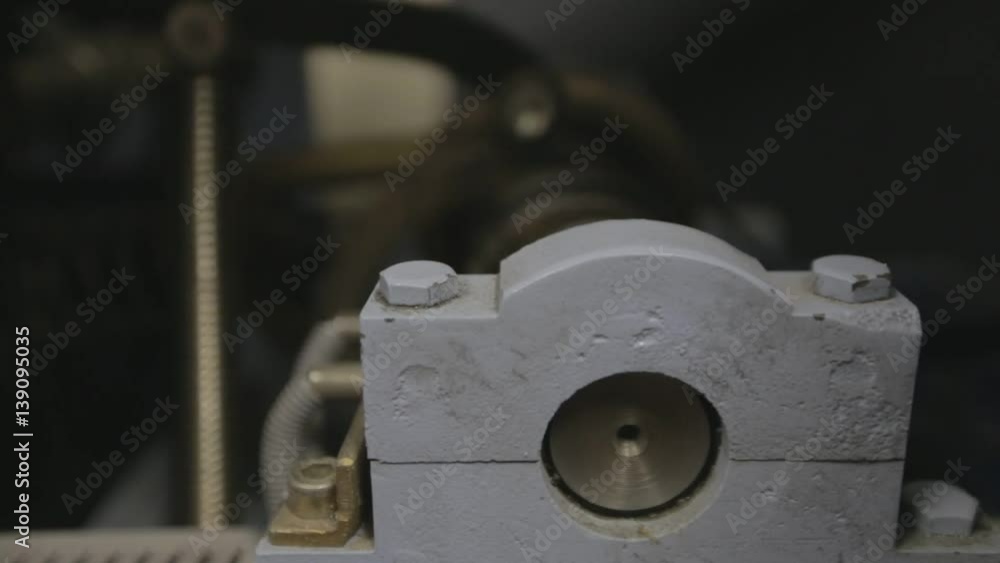 Old automated line for making packaging production. Industry equipment. The mechanism rotates and drives the conveyor. Steady yellow light. Steam punk concept Old automated line for making packaging production. Industry equipment. The mechanism rotates and drives the conveyor. Steady yellow light. Steam punk concept
