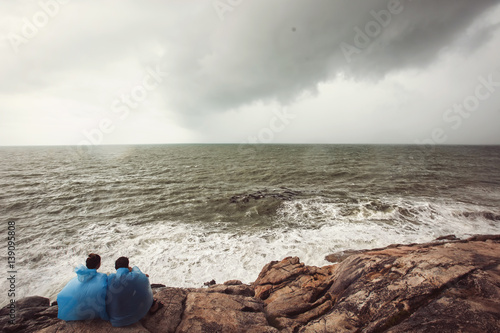 Love couple sitting and looking on the Sea storm. Big ocean wave breaking the shore © Annatamila