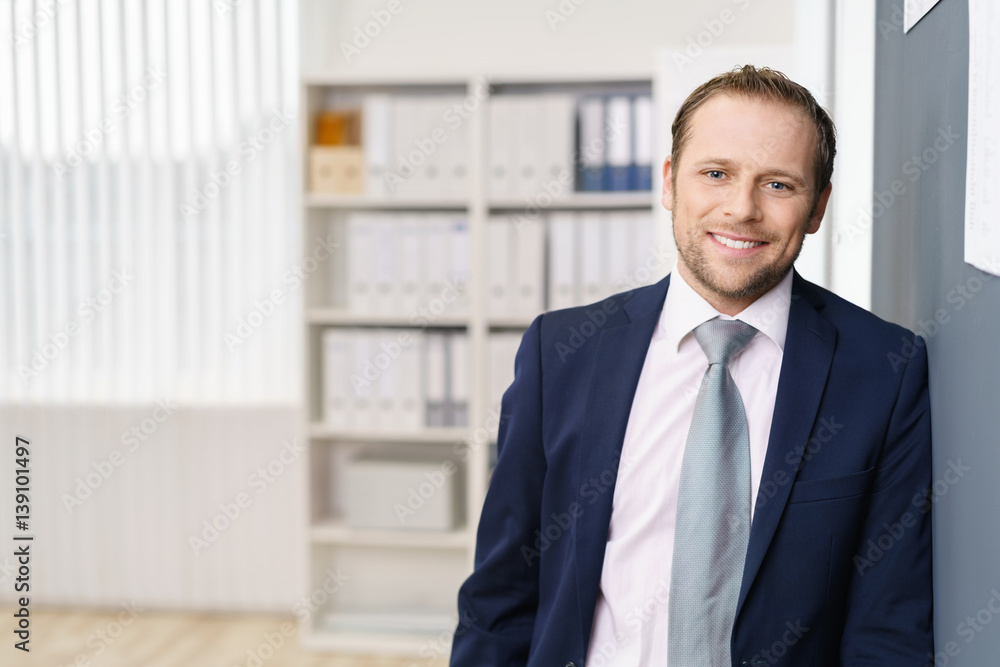 erfolgreicher geschäftsmann lehnt sich lässig an einer wand im büro erfolgreicher geschäftsmann lehnt sich lässig an einer wand im büro