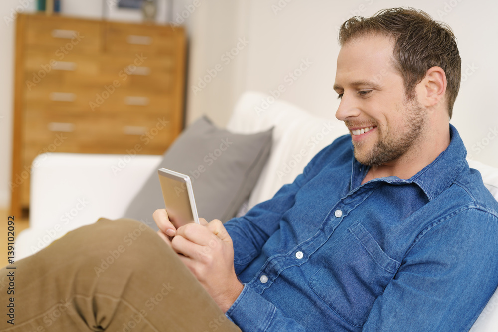 Obraz premium mann mit mobiltelefon zuhause auf dem sofa