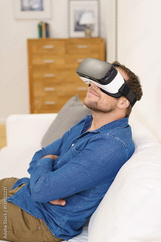 Obraz premium mann sitzt entspannt auf dem und schaut durch eine vr brille