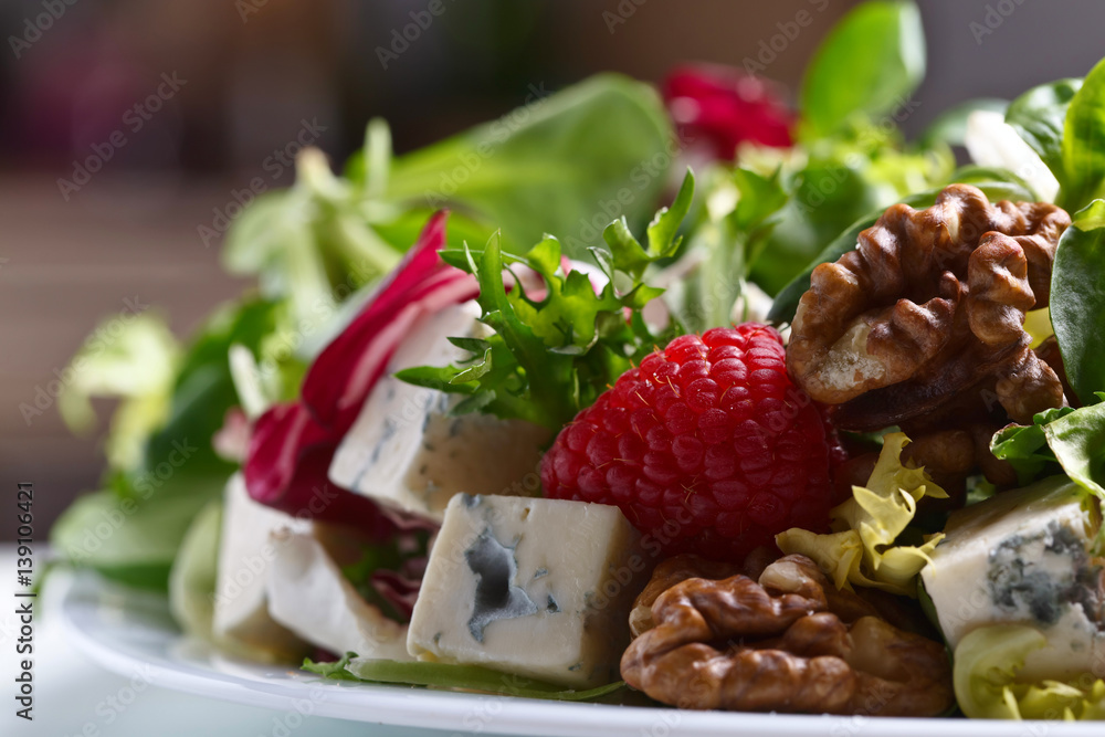 Green spring salad with blue cheese , raspberry and nuts
