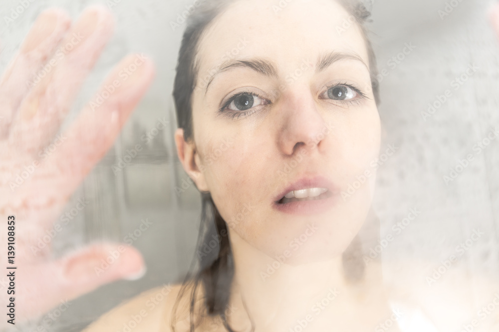 Naklejka premium Stressed woman leaning on weeping glass shower door