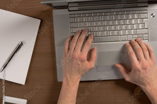 Man sitting at desk and working at computer hands close up photo