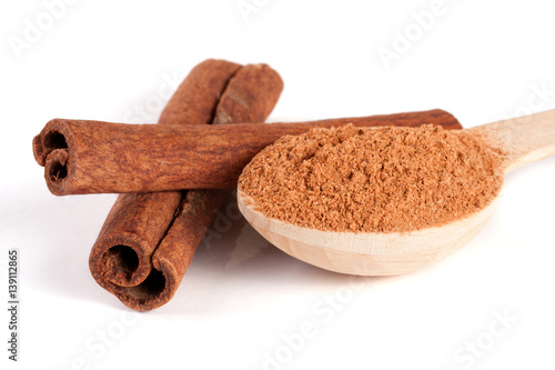 two cinnamon sticks and powder with spoon isolated on white background