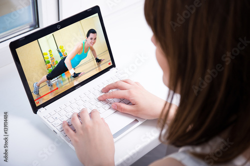 video blog concept - young woman watching on laptop video about sport