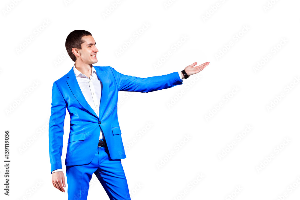 Young elegant business man in blue suit is pointing at free space isolated at white background. Young elegant business man in blue suit is pointing at free space isolated at white background.