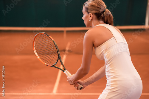 View from the back on a female tennis player on a court indoor