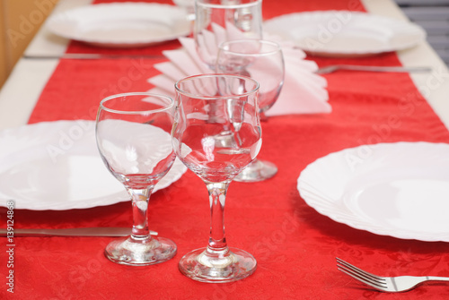 Two wine glass on a red tablecloth, decorated table,