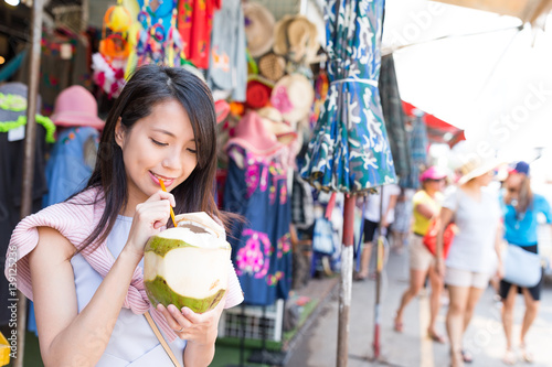 Woman drinking of coconut at street market