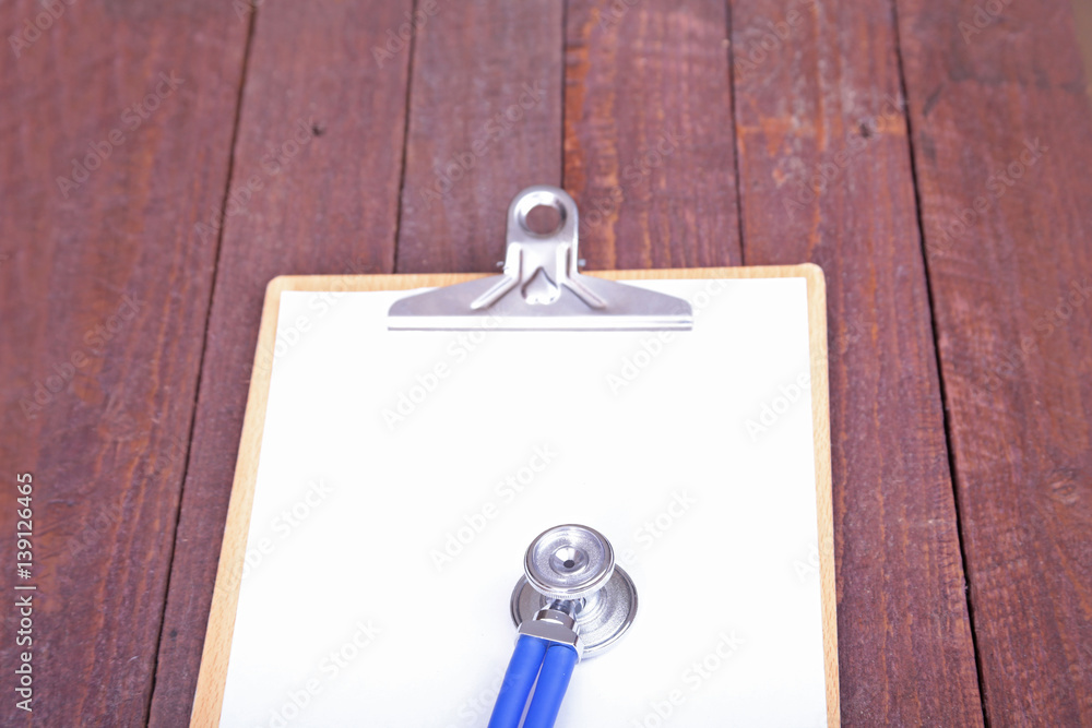 Closeup of a medical stethoscope with folder on wooden background