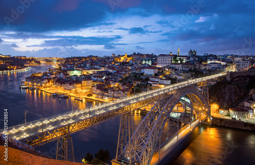 View of the historic city of Porto, Portugal with the Dom Luiz bridge at dusk.