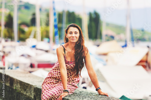 Outdoor summer portrait of a beautiful brunette woman resting by the lake