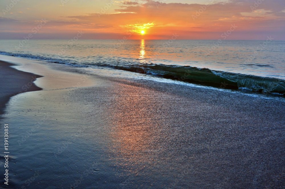 Fototapeta premium Waves Breaking Beneath a Sunrise on the Beach