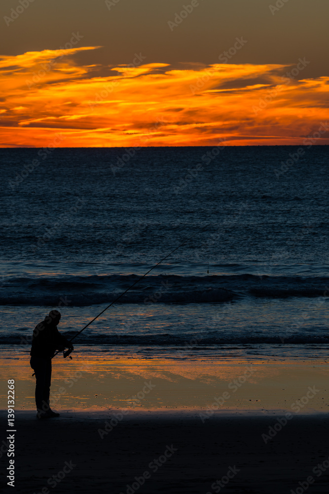 Angler with fishing rod on the beach
