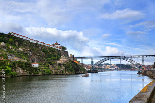 Vista panoramica da Ponte Dom Luis na cidade do Porto, com barcos turísticos a passearem no Rio Douro