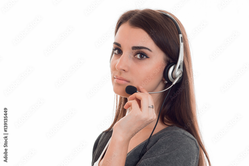 Portrait of serious young girl in headphones that corrects hand microphone is isolated on a white background Portrait of serious young girl in headphones that corrects hand microphone is isolated on a white background