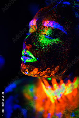 Beautiful extraterrestrial model woman in neon light. It is portrait of beautiful model with fluorescent make-up, Art design of female posing in UV with colorful make up. Isolated on black background photo