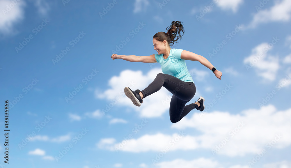 happy smiling sporty young woman jumping in sky