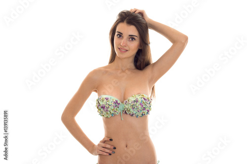 a young girl in a bathing suit with beautiful breasts keeps his hand on the side and the second hand keeps hair