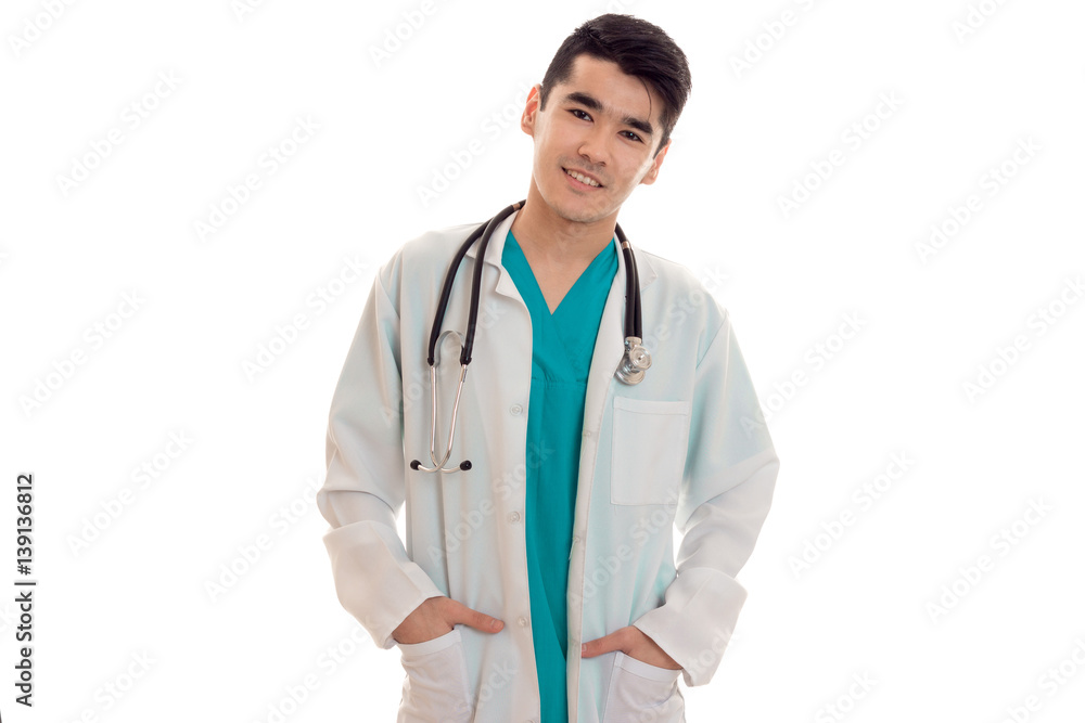 young pretty brunette male doctor in uniform with stethoscope on his neck posing on camera isolated on white background young pretty brunette male doctor in uniform with stethoscope on his neck posing on camera isolated on white background