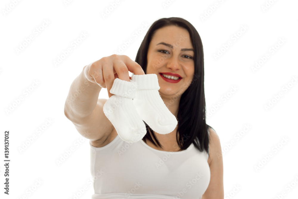 young pregnant brunette girl with little socks in her hands looking and smiling on camera isolated on white background young pregnant brunette girl with little socks in her hands looking and smiling on camera isolated on white background