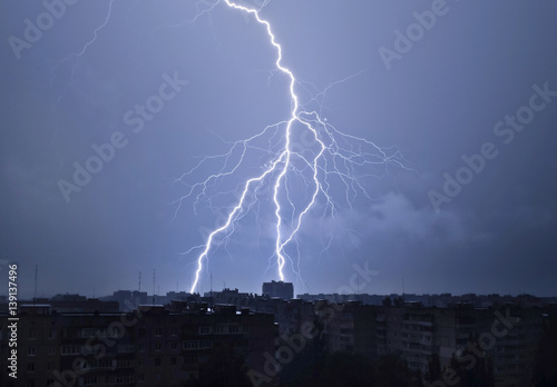 Lightning in the night sky strikes the roof of the house