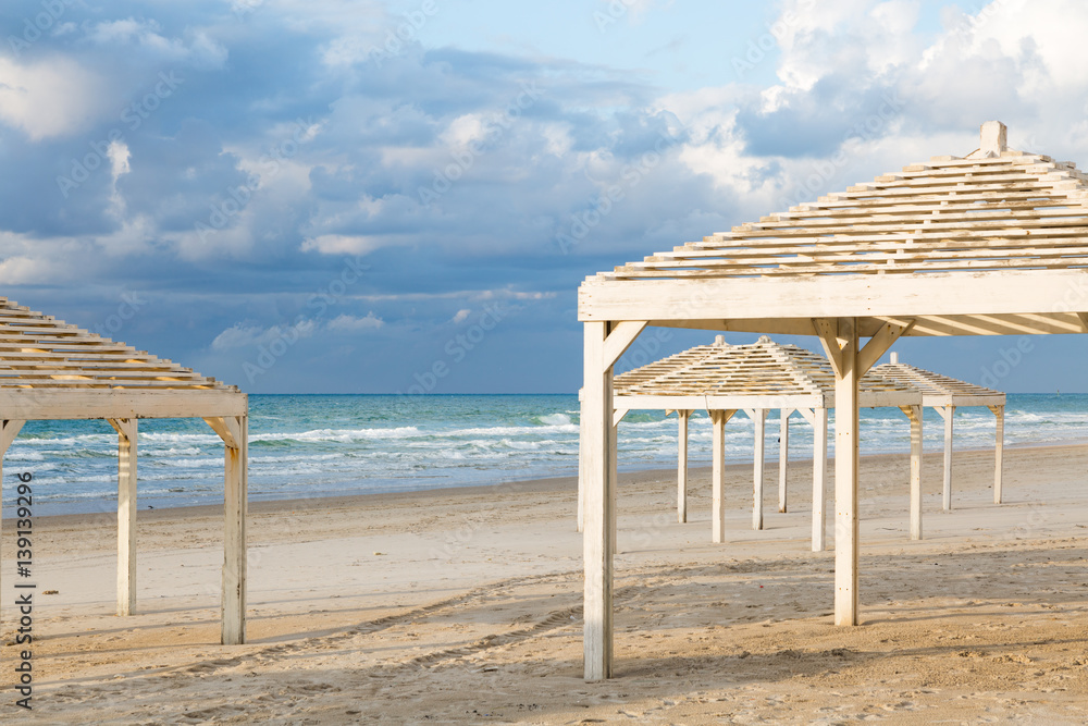 White sunshades on beautiful beach and cloudy sky. Travel and vacation concept.