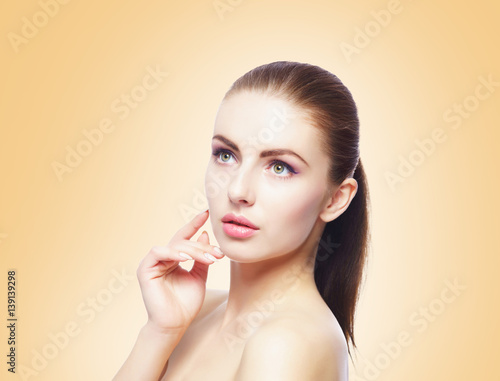 Portrait of young, beautiful and healthy woman: over yellow background. Healthcare, spa, makeup and face lifting concept.