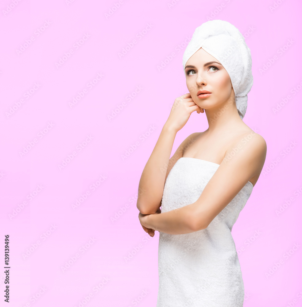 Young, beautiful and natural woman wrapped in towel over pink background. Young, beautiful and natural woman wrapped in towel over pink background.