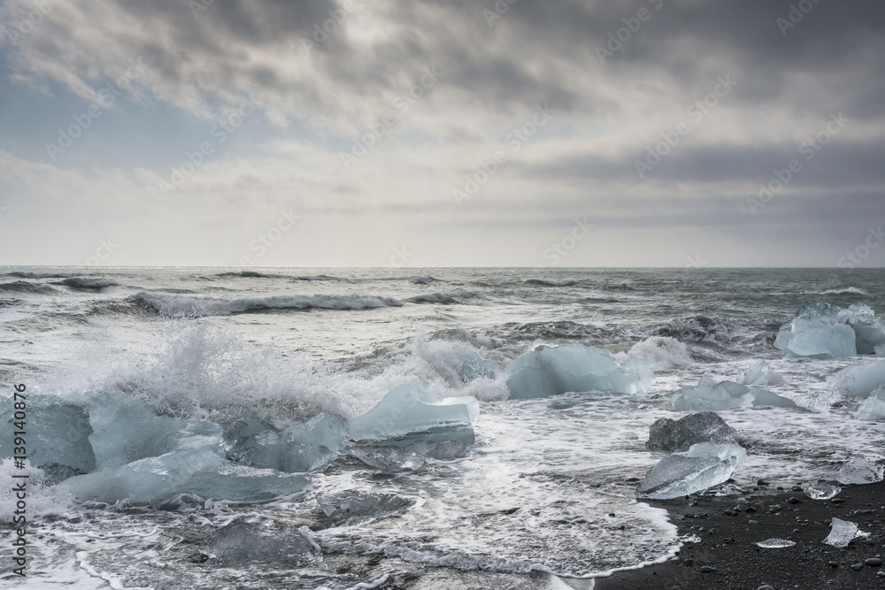 Waves of Atlantic ocean crash against icebergs at Jokulsarlon glacial lagoon near Vatnajokull National Park, southeast Iceland