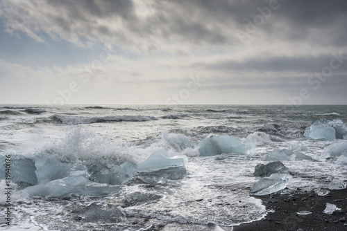Waves of Atlantic ocean crash against icebergs at Jokulsarlon glacial lagoon near Vatnajokull National Park, southeast Iceland