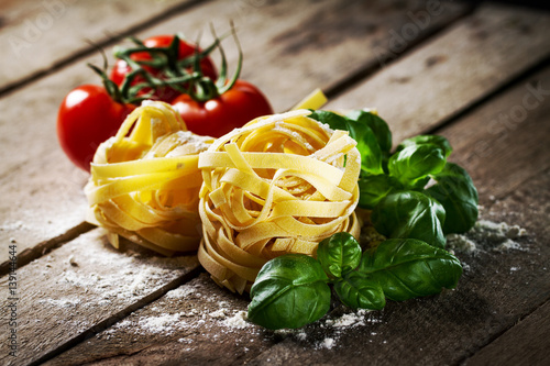 Tasty Fresh Colorful Ingredients for Cooking Pasta Tagliatelle with Fresh Basil and Tomatoes. Wooden Table Background. photo