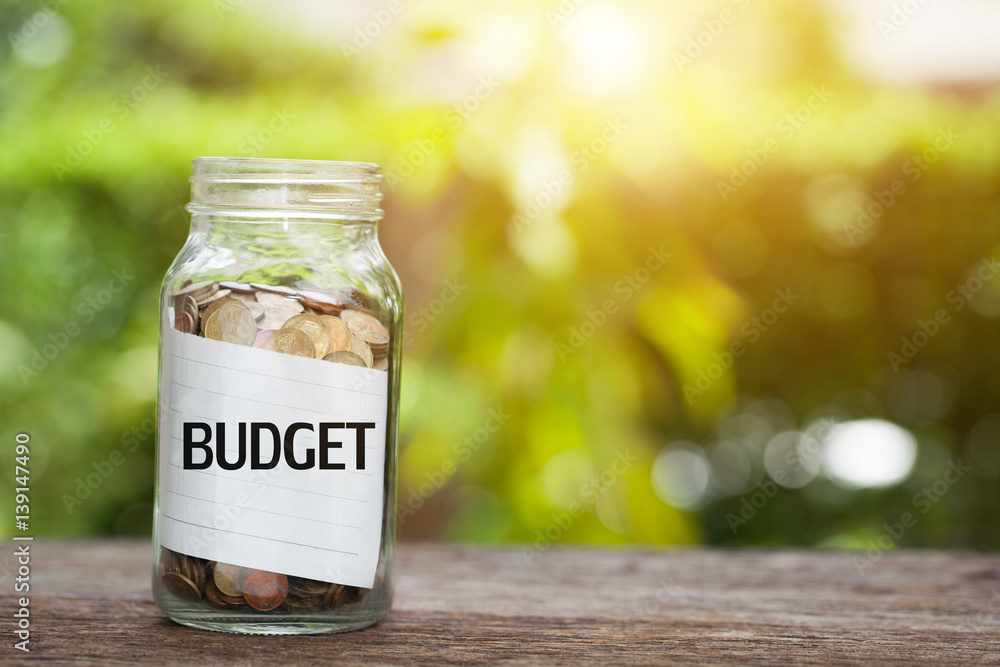 BUDGET word with coin in glass jar with Savings and financial investment concept. BUDGET word with coin in glass jar with Savings and financial investment concept.