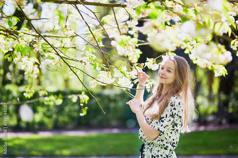 Beautiful young woman in blooming spring park