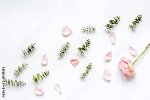 floral pattern with rose petals and eucalyptus on white table top view