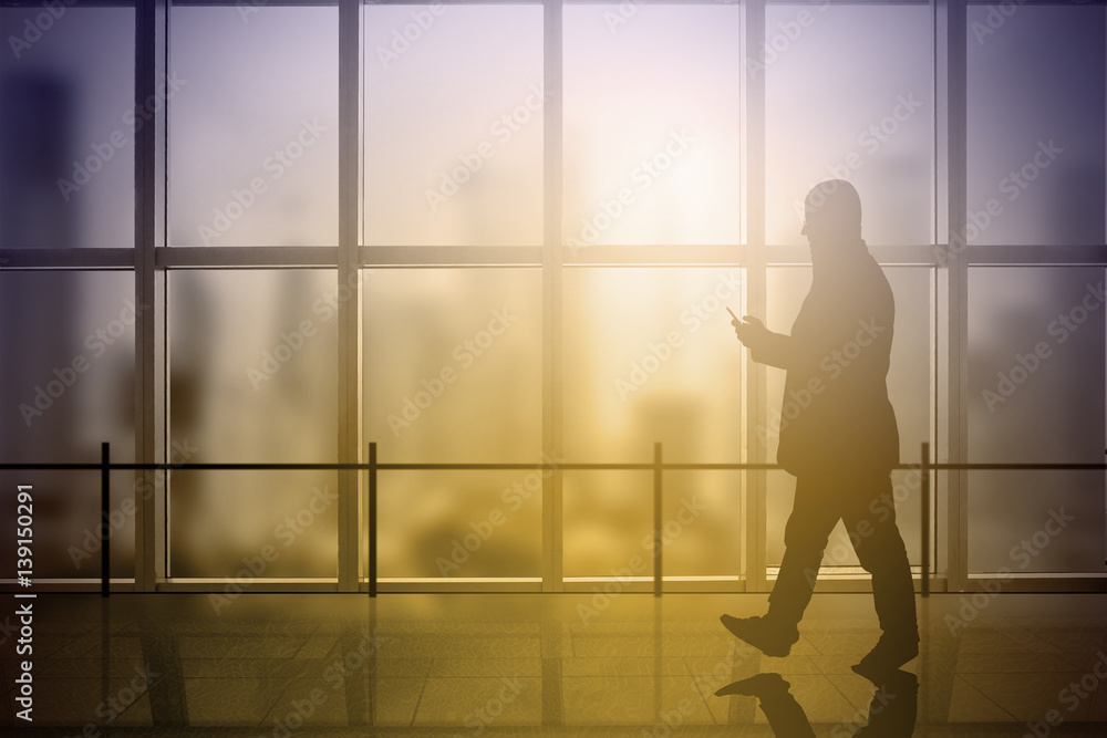 Business man using a mobile while walking a office building corridor. Sun flare. Empty copy space for Editor's content. Business man using a mobile while walking a office building corridor. Sun flare. Empty copy space for Editor's content.