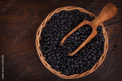 Black beans in scoop on wooden background