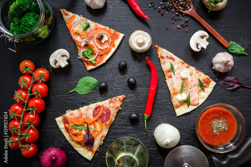 Delicious pizza with ingredients and spices on dark table. Flat lay, top view.