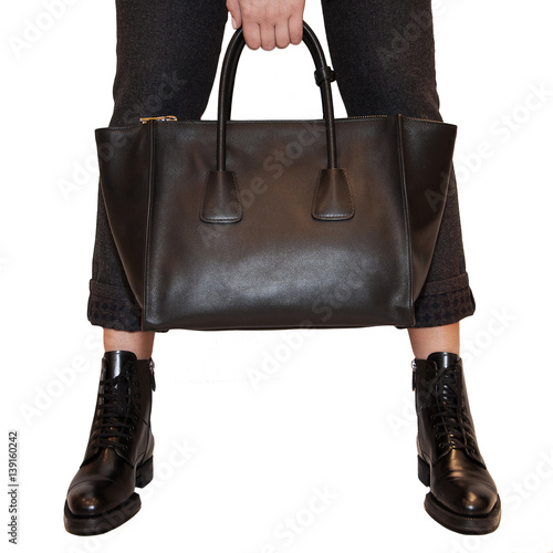 Fashionable woman holding leather black bag. Elegant outfit. Close up of purse in hands of stylish lady. Insolated on white background. Without face. Female fashion. City lifestyle.