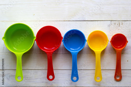 Colorful measuring spoons for kitchen on a white wooden background