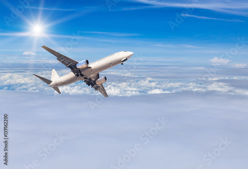 airplane flying away in to sky high altitude above the white clouds with sunlight