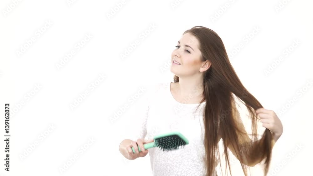 Woman brushing her healthy hair with big green brush. Young female with beauty straight long brown hairs, studio shot isolated on white background 4K ProRes HQ codec Woman brushing her healthy hair with big green brush. Young female with beauty straight long brown hairs, studio shot isolated on white background 4K ProRes HQ codec