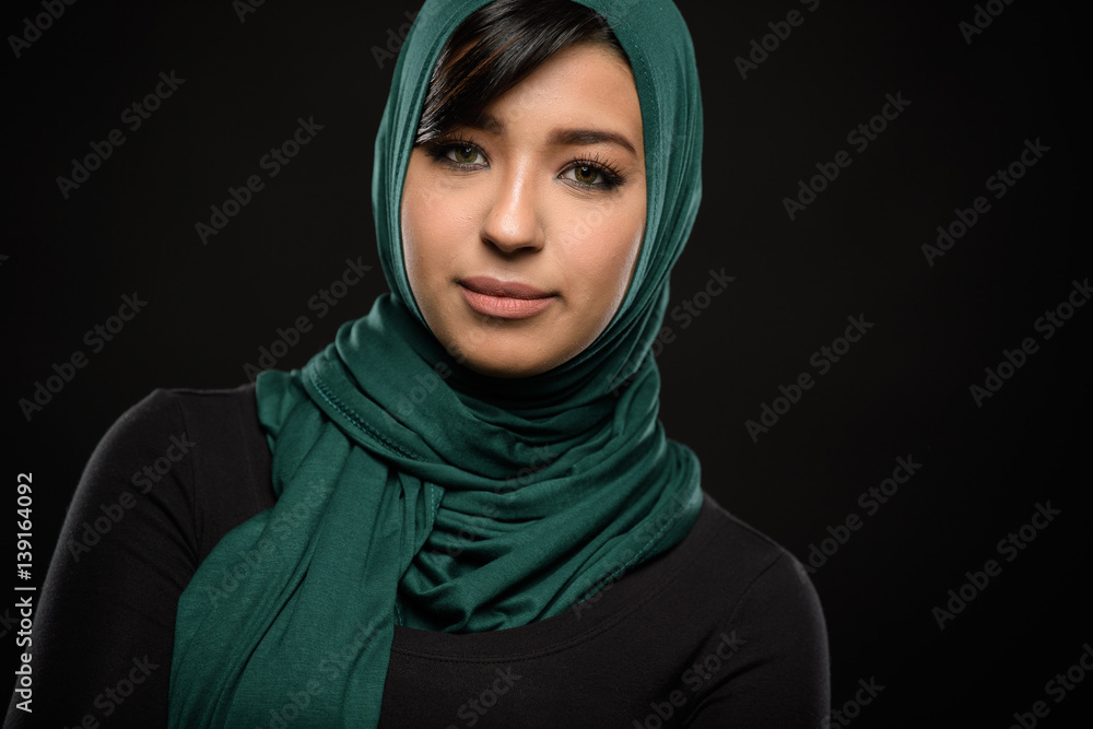 Portrait of a beautiful Muslim woman dressed in hijab on a black background in photo studio. Portrait of a beautiful Muslim woman dressed in hijab on a black background in photo studio.