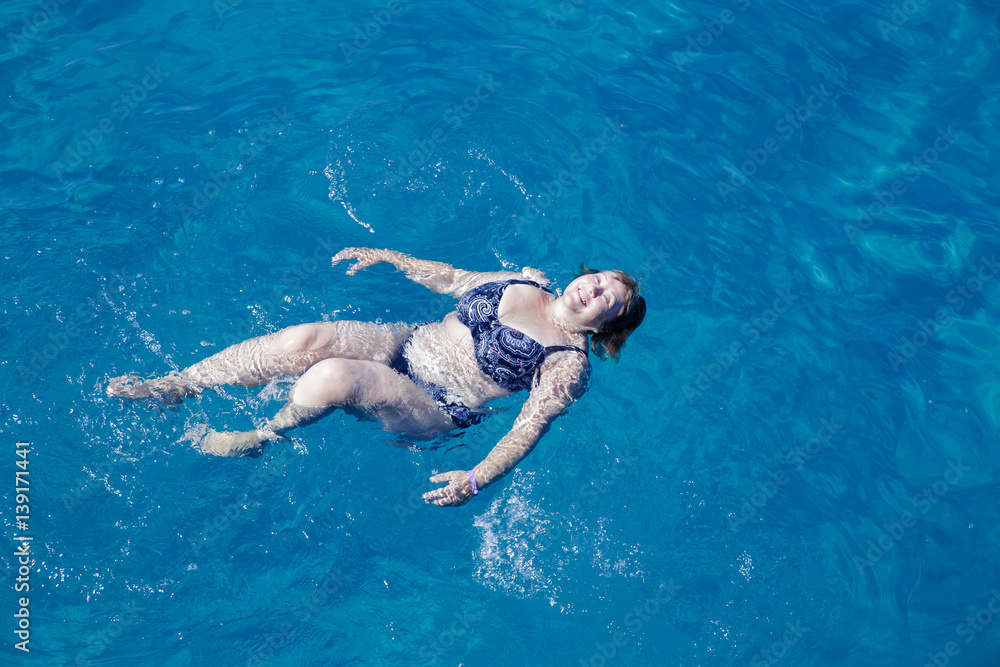 Active senior woman swimming in blue sea water