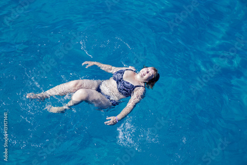 Active senior woman swimming in blue sea water