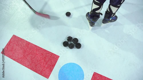 Close-up of ice hockey pucks. View from above: the hockey puck in the center of the ice rink and hockey sticks. Hockey training - drawing the puck. photo