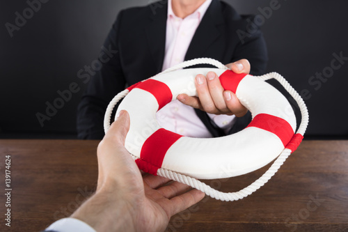 Businessman Passing A Lifebuoy To A Partner photo