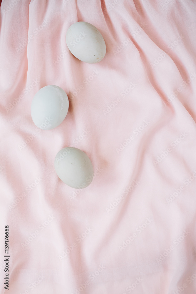 White Easter eggs on pink textile background. Flat lay, top view. White Easter eggs on pink textile background. Flat lay, top view.