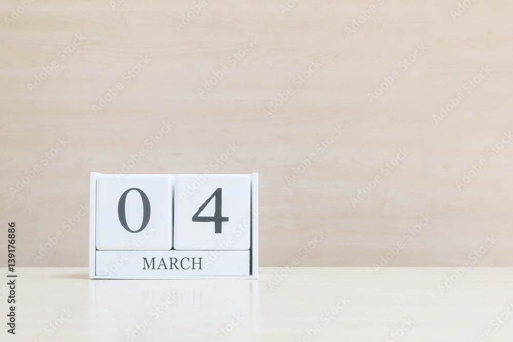 Closeup surface white wooden calendar with black 4 march word on blurred brown wood desk and wood wall textured background with copy space , selective focus at the calendar